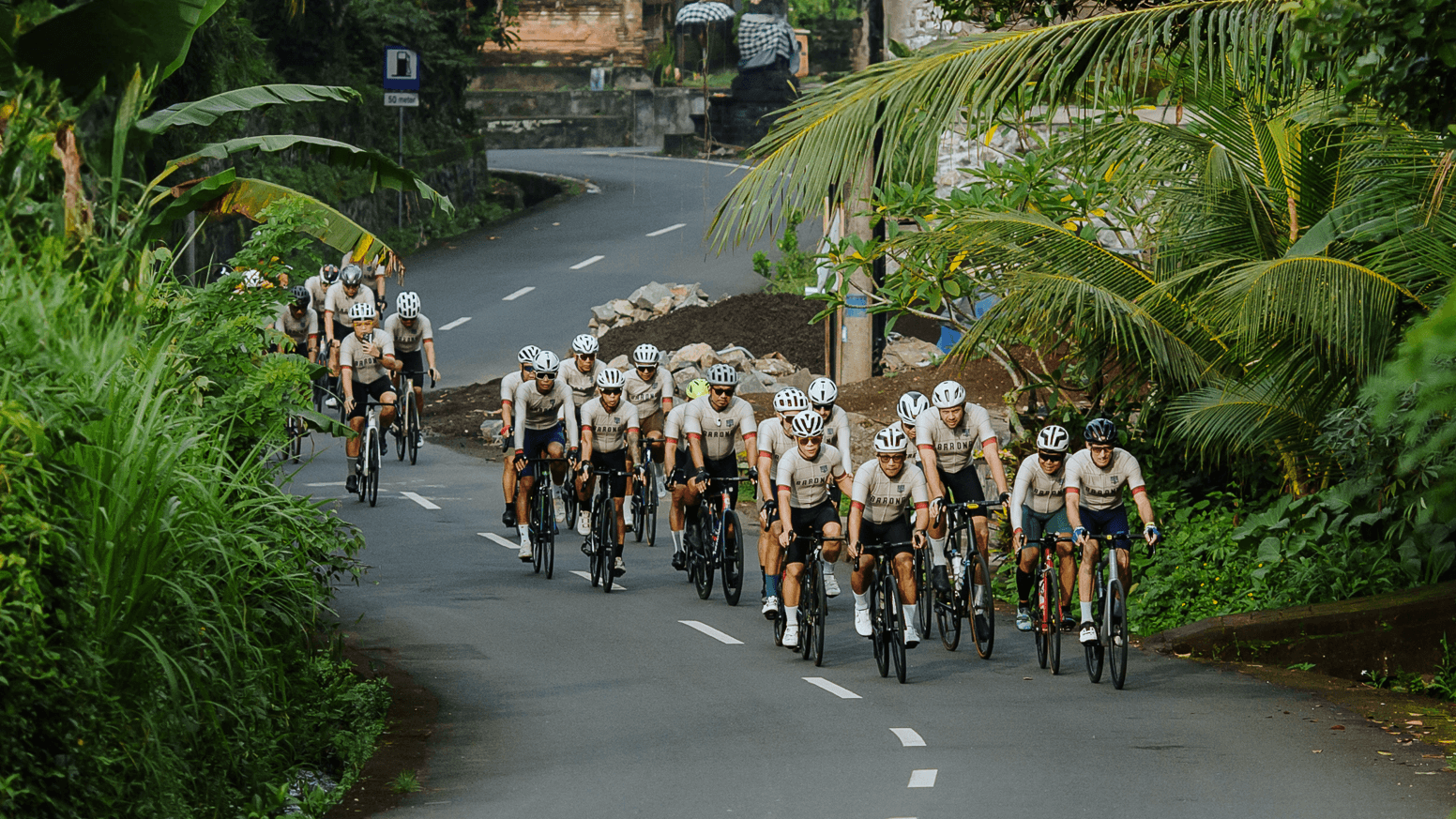 Cyclists riding through Bali at golden hour with Mount Agung in the distance